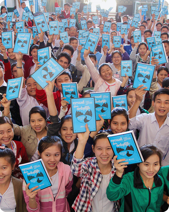 Large group from Asia holding up translated Driven by Eternity book by author John Bevere